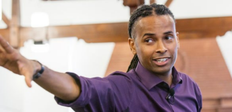 LeDerick Horne with his hand outstretched giving a presentation LeDerick Horne with his hand outstretched giving a presentation