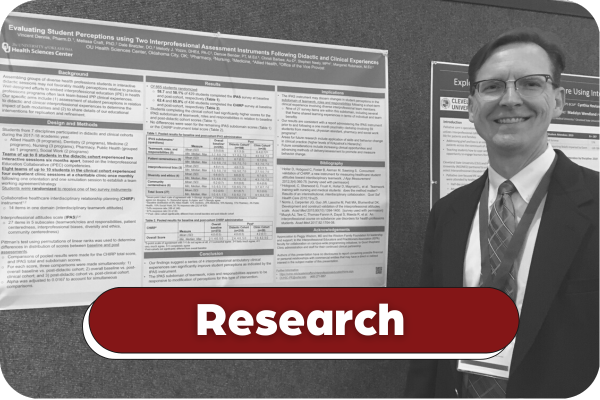 Black and white image of Dr. Vince Dennis smiling in front of his research poster. Title on image says "Research".